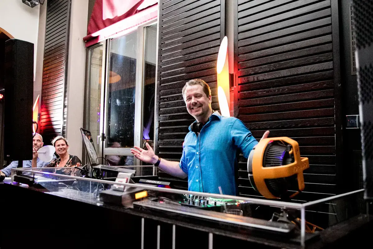 DJ Chris Force hinter dem beleuchteten DJ-Pult, Gäste stehen daneben