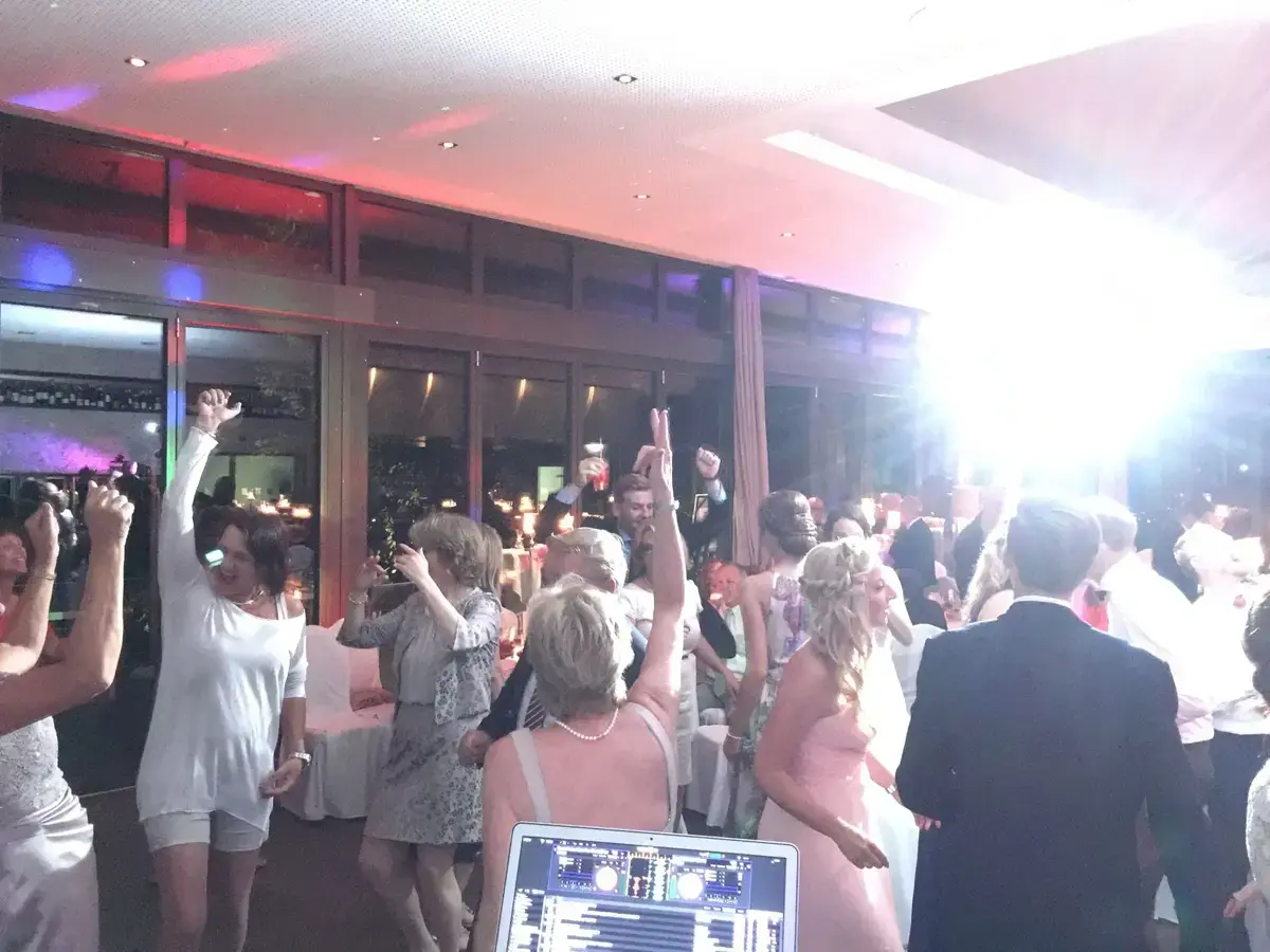 Hochzeitsgesellschaft mit erhobenen Armen auf der Tanzfläche, DJ-Pult im Vordergrund – Event mit DJ Chris Force in Gießen